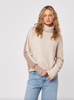 Woman wearing a beige sweater and blue jeans on a white background