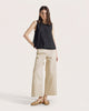 Woman wearing a black sleeveless top and beige wide-leg pants on a white background